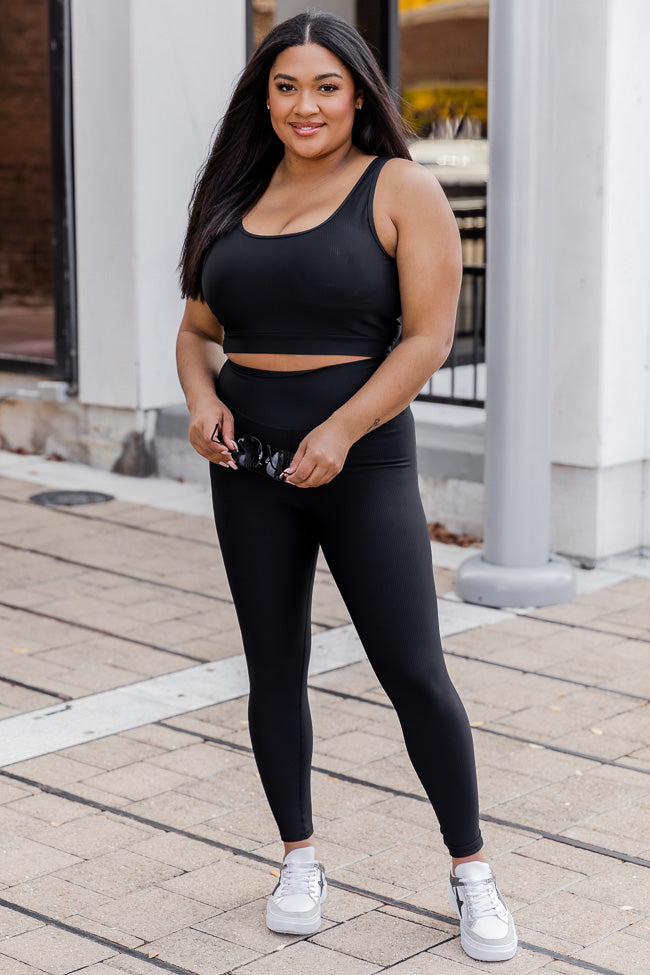 A 24 year old woman brunette woman in a black top, pink leggings